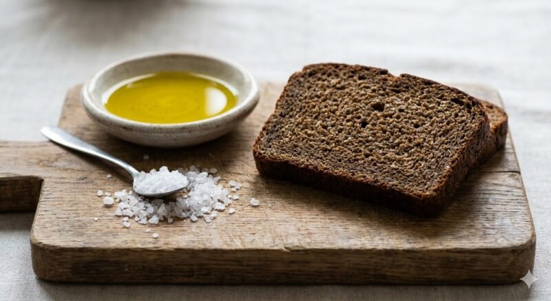 ライ麦パンのお供、オリーブオイルと天然塩の実撮。スライスしたライ麦パンに添えられた、小皿に入った良質なオリーブオイルと粗塩の写真
